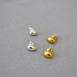 Macro detail of oval bean stud earrings with polished gold and silver mirror finish