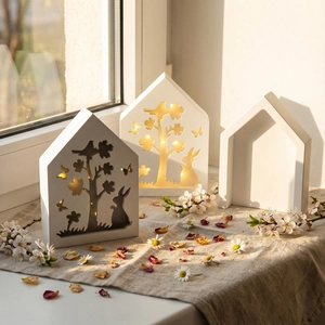 Detail of wooden bunny house lamp with warm LED lights and intricate forest carvings
