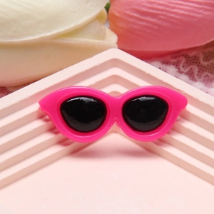 Rose red mini resin cat eye sunglasses charm for DIY crafts on a textured pink base