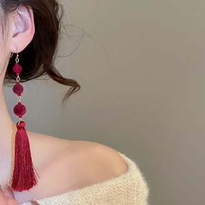 Macro view of bridal red flocked bead earrings with long silk tassels and gold accents