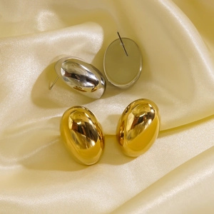 Polished gold and silver oval hollow earrings on elegant yellow satin fabric