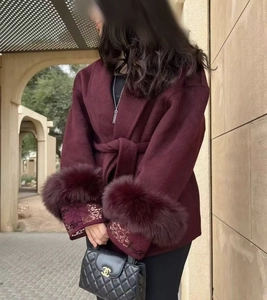 Detailed view of burgundy coat with luxurious faux fur cuffs and delicate lace sleeve trims