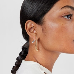 Boucles d'oreilles pendantes courbées bicolores en acier portées par un mannequin
