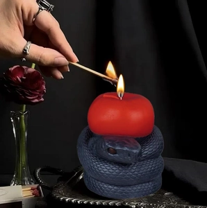 Gothic style red apple candle atop a detailed black coiled snake base on silver tray