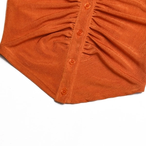 Dettaglio del top in maglia a coste arancione con abbottonatura e design arricciato
