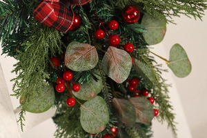 Detailed close-up of Eucalyptus Christmas door swag with red berries and plaid bow