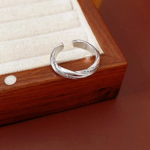 Detailed view of silver twisted ring with shimmering zircons on brown leather backdrop