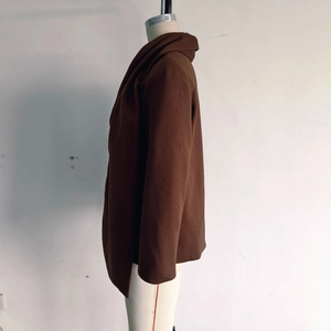 Detailed side view of dark brown wool coat with premium textured wool fabric and long-line cut