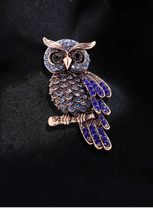 Macro detail of luxury owl brooch with blue rhinestones on black silk background