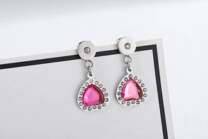 Macro shot of silver heart drop earrings with pink center stone and white rhinestones