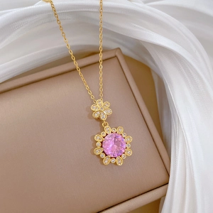 Detailed close-up of a golden flower pendant with a pink gemstone on soft white silk
