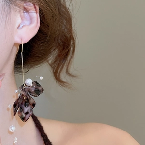 Detail view of long tassel earrings with acrylic flower petals and white pearls on a model