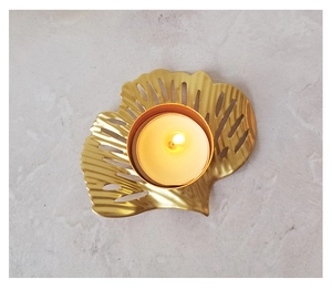 Top view of creative golden leaf candle holder with a lit tealight on grey stone