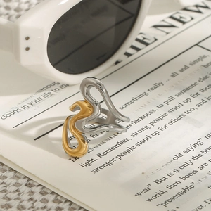 Anello astratto bicolore in acciaio al titanio su sfondo di giornale d'epoca con occhiali