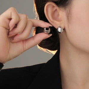 Minimalist silver spherical hoop earrings shown on model with polished metallic finish
