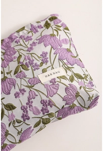 Close-up of lilac floral woven fabric texture and brand label on a canvas makeup bag