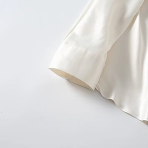 Detail of white satin shirt showing the batwing sleeve cuff and lustrous silk fabric texture