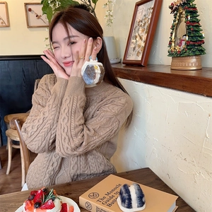 Close-up of plush headphone case with zipper and hook in a cozy cafe setting