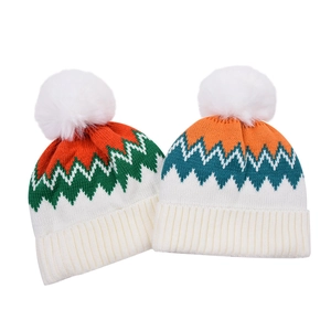 Detail view of colorful knit beanies with geometric wave patterns and faux fur pom-poms