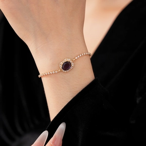 Detail of adjustable gold bracelet featuring a deep purple oval gem and pavé crystals