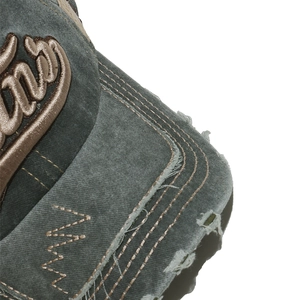 Macro detail of distressed washed cotton brim with 3D embroidery and frayed edge textures