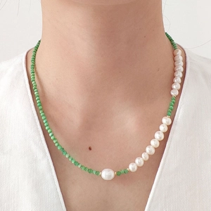 Detail of beaded necklace with cat eye stones, pearls and golden heart pendant