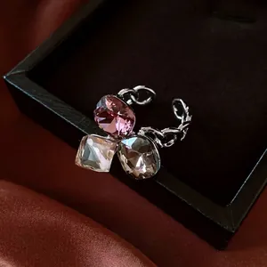 Bague chaîne argentée moderne avec zircons carrés roses, clairs et gris sur velours