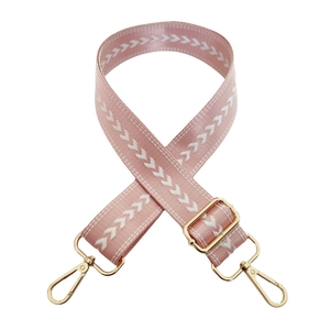 Detail of adjustable pink nylon wide strap with white arrow pattern and gold metal hooks