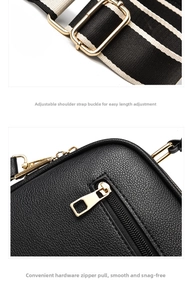 Detail of black pebbled leather crossbody bag with striped strap and gold-tone metal hardware