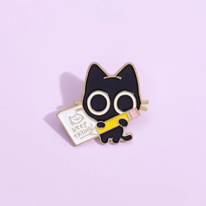 Detail of cartoon black cat enamel pin with pencil and Keep Trying text on purple background