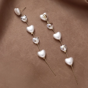 Elegant gold chain earrings with white heart pearls and clear crystals on brown silk