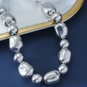 Macro shot of mirror-polished silver geometric beads on a minimalist punk choker necklace