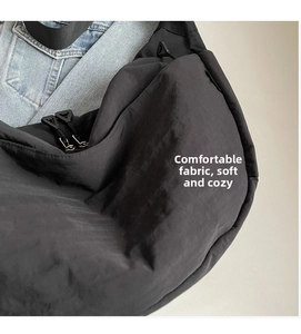 Detail of soft matte black nylon fabric and zipper on a large crossbody hobo bag