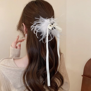 Detail of white feather and satin ribbon hair claw clip styled on a semi-updo hairstyle