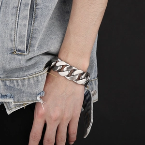 Close-up of matte silver stainless steel Cuban link bracelet worn on a male wrist