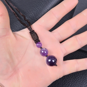Natural amethyst beaded necklace with brown woven cord held in hand on leather background