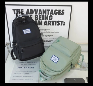 Detail of minimalist fabric backpacks in black and green with front zipper pockets