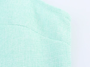 Close-up of light green tweed fabric texture for a sleeveless two-piece mini dress