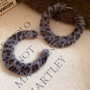Detail of leopard print plush fabric earrings with a circular C-shaped fashion design