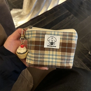 Detail of vintage blue checkered coin purse with cupcake charm held by hand