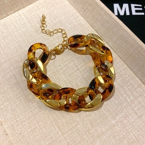 Detail of vintage gold chain bracelet with amber resin links on a textured beige tray