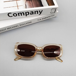 Detailed top view of vintage amber oval sunglasses on a minimalist fashion book background