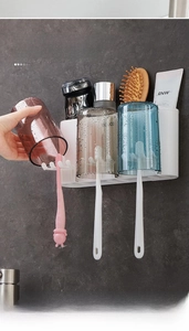 Wall-mounted toothbrush holder detail with three colorful cups and storage shelf