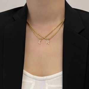 Détail du collier doré en titane à double rangée avec pendentifs lettres L et R en zircon