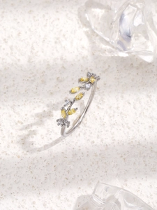 Detail shot of silver leaf ring with yellow marquise zircon on a textured white background
