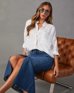 Dettaglio della gonna lunga in denim con spacco a vita alta e camicia in cotone bianco