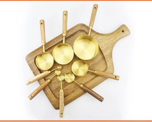 Top view of gold stainless steel measuring cups and spoons set with acacia wood handles