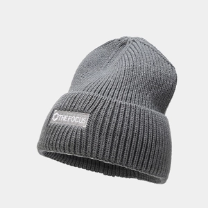 Detailed macro view of dark grey ribbed knit beanie featuring The Focus logo patch
