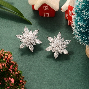 Silver snowflake earrings with zircon stones on festive Christmas background decor