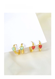 Detail of gold-plated heart earrings with red and green cubic zirconia on silk cloth
